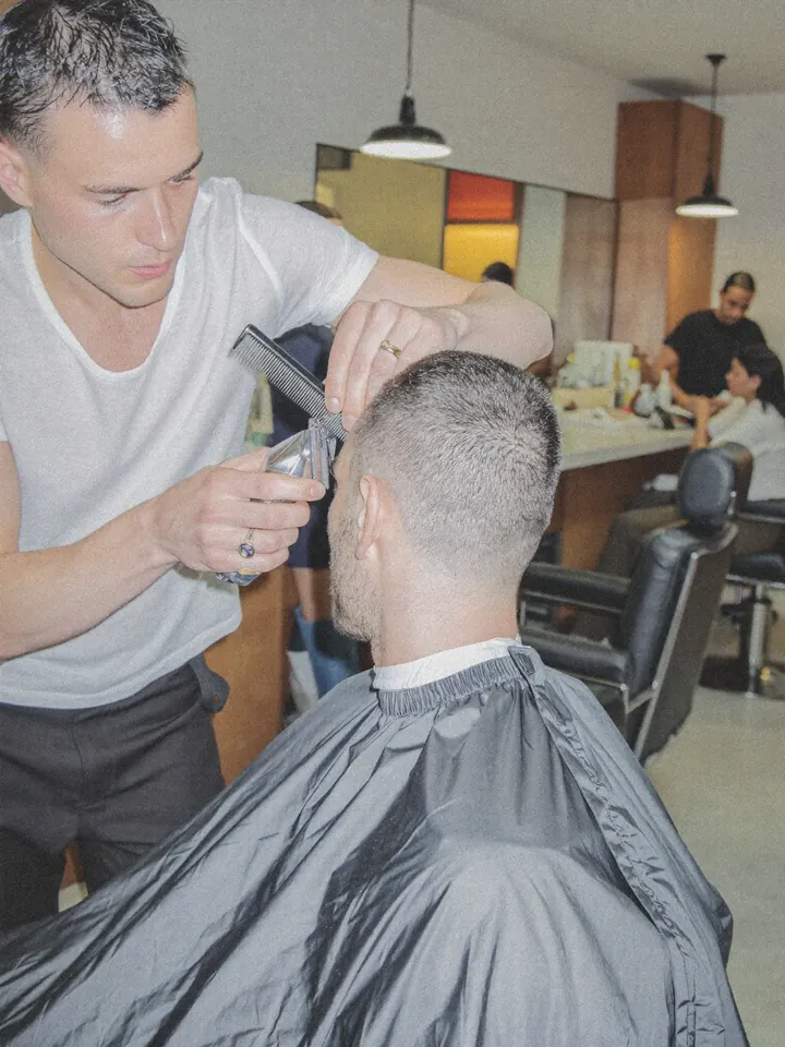 A barber giving a client a short cut with clippers